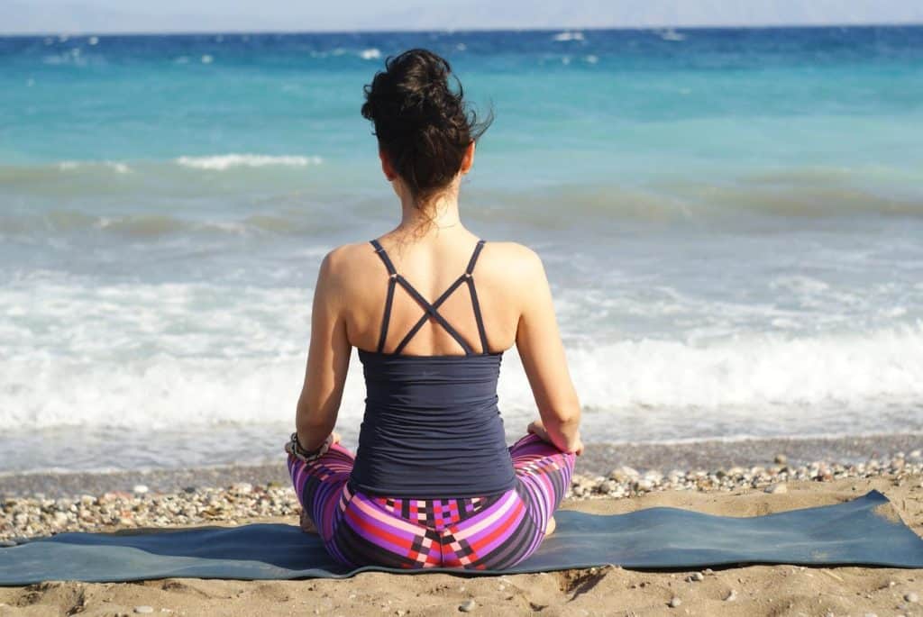 Girl practicing meditations at the beach.