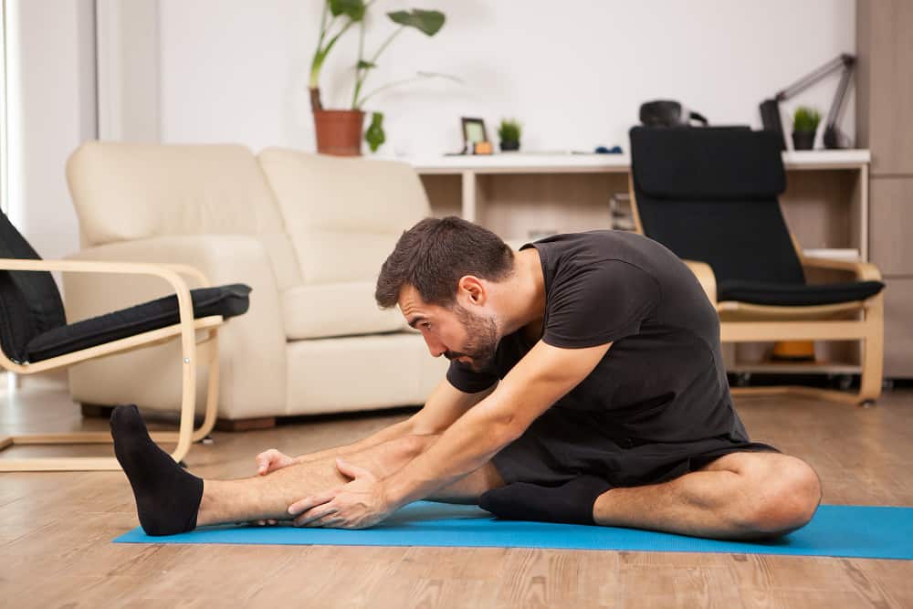 living room yoga man performing bodyweight hamstring exercises