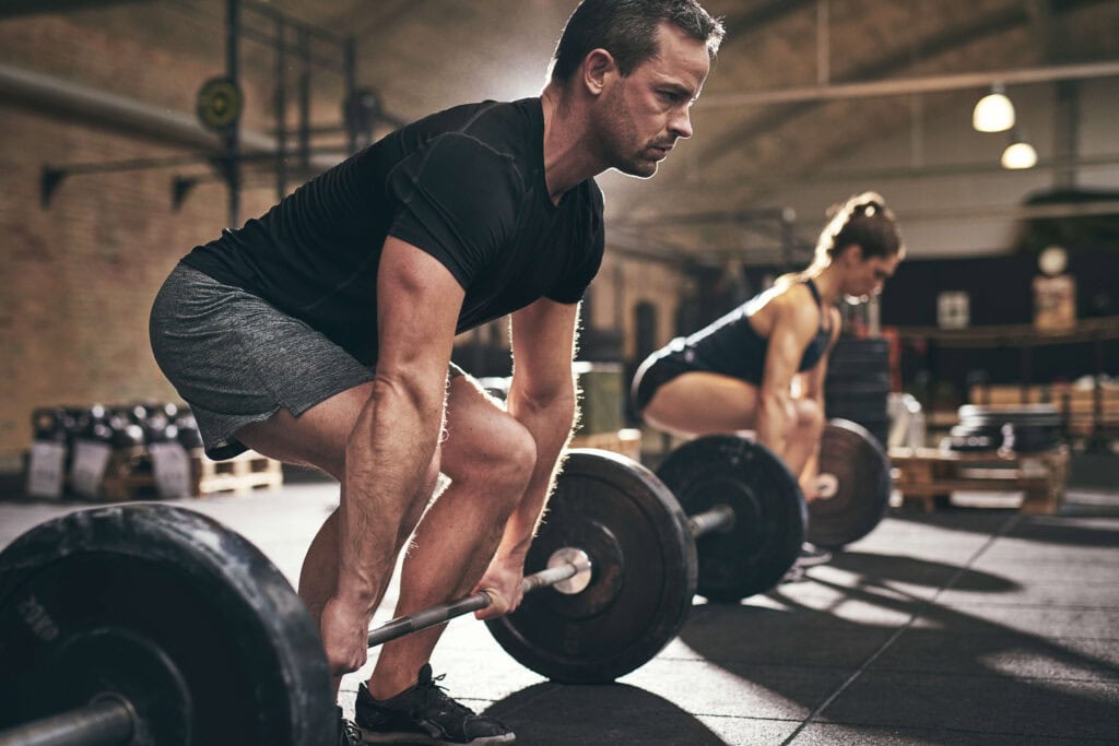 man and woman learning how to deadlift